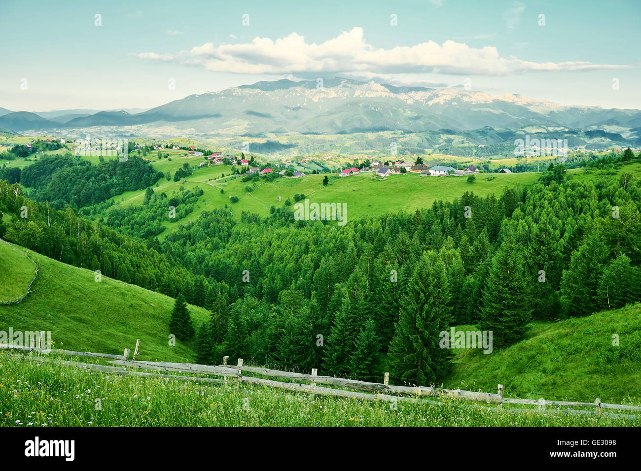Paese vista laterale dall'alto, piccolo villaggio e foresta verde, cielo blu con nuvole Foto Stock