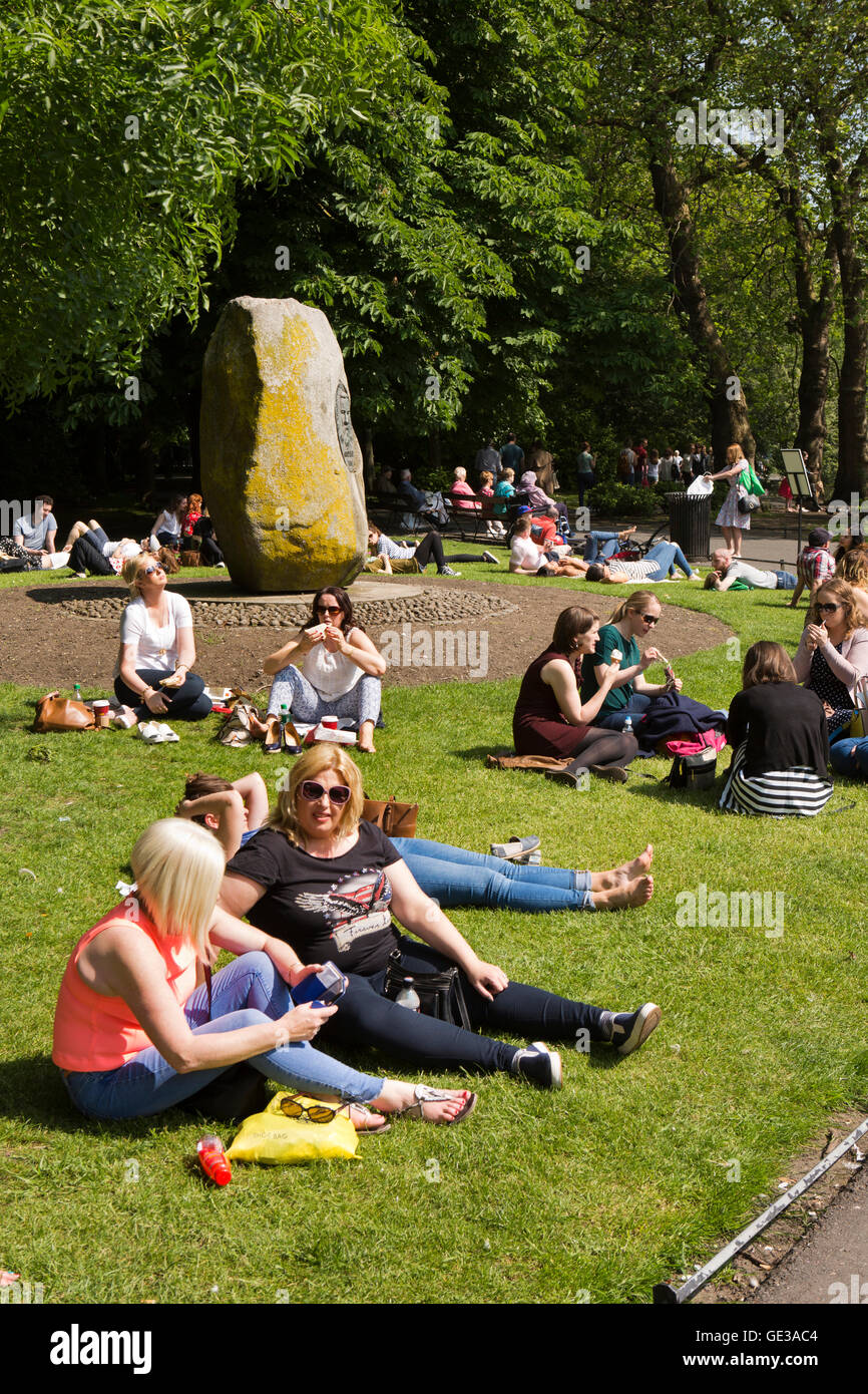 Irlanda, Dublino, St Stephen's Green, la gente seduta nella luce del sole da un monumento a Geremia O'Donovan Rossa Foto Stock