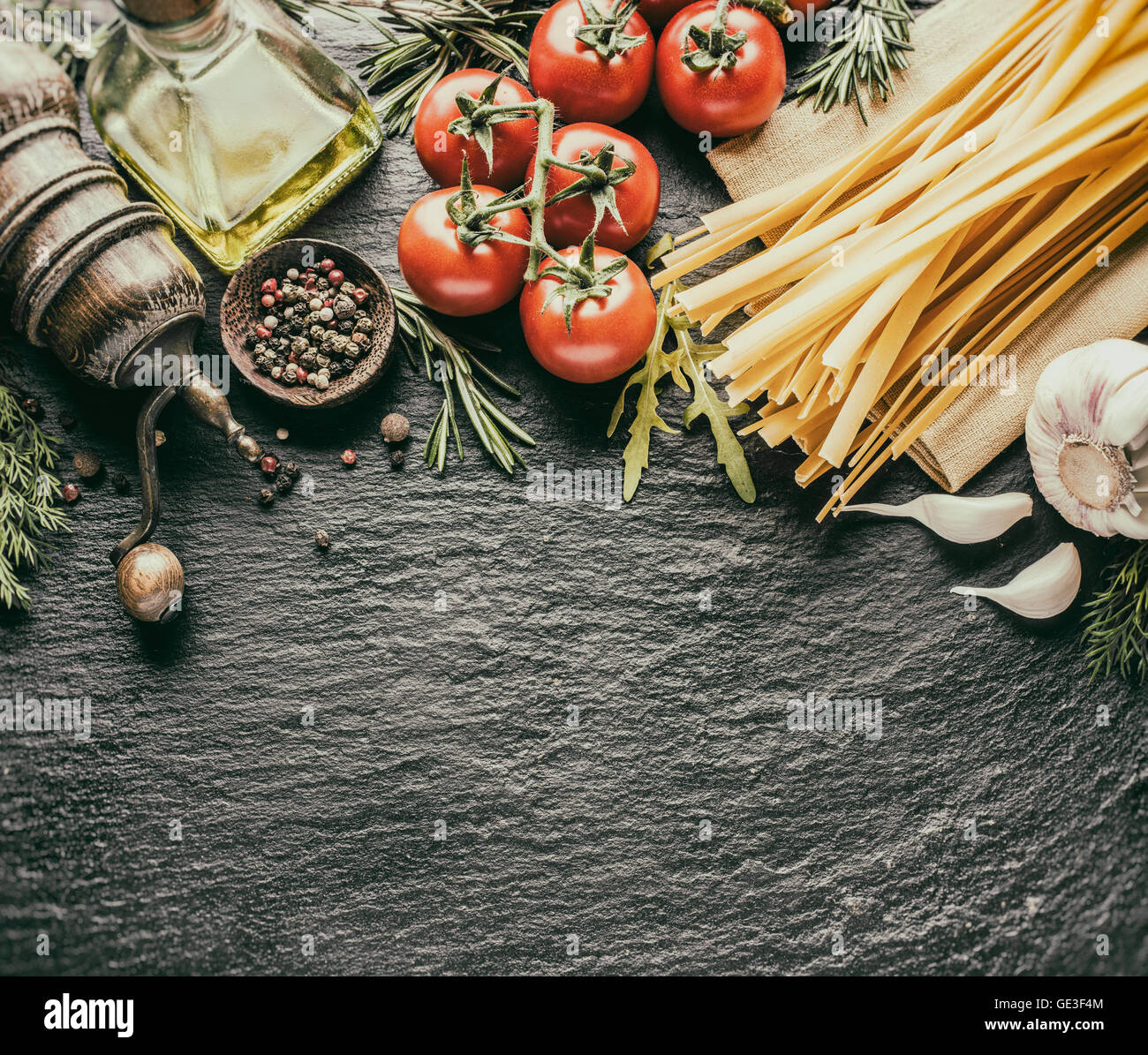 Ingredienti per la pasta. Cherry-pomodori, spaghetti, rosmarino e spezie su una scheda di grafite. In stile vintage. Foto Stock
