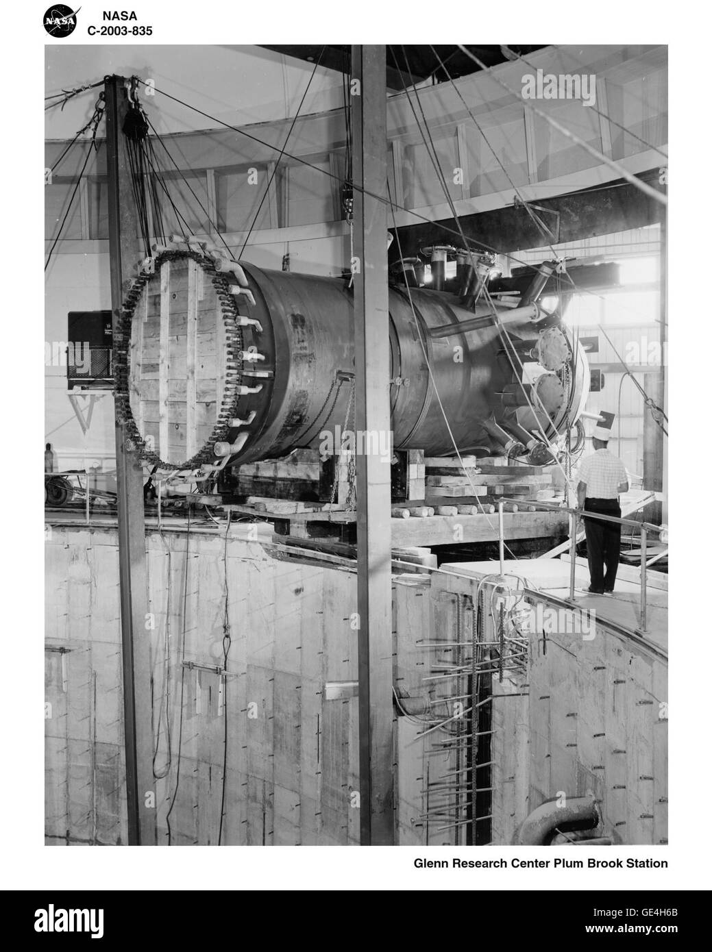 Questa immagine mostra un serbatoio a pressione in fase di preparazione per essere abbassato in un serbatoio di contenimento. L'immagine è etichettata come C-2003-835, che può riferirsi a una fase specifica dell'installazione di apparecchiature in un impianto industriale o nel settore dell'energia. Mette in evidenza i processi meticolosi coinvolti nella configurazione di recipienti a pressione utilizzati per lo stoccaggio di energia o il contenimento. Foto Stock