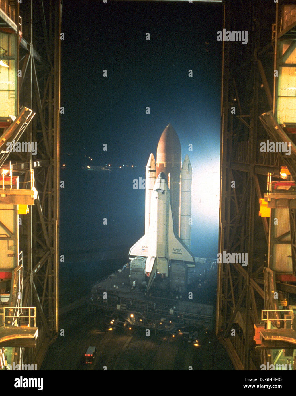 Una vista dall'interno bay tre del gruppo di veicoli Edificio (VAB) mostra la navetta spaziale Discovery lavato in bianco luce allo xeno come fa una partenza notturna dal VAB sul suo modo di pad 39B. La scoperta è stata rolling out a battere la missione STS-26. Il payload primario è stato il TDRS-C satellite. Il primo movimento nella navetta di spostarsi dalla VAB verso il tampone è venuto a 12:50 a.m. Luglio 4, 1988. Immagine # : 88PC-0675 Data: 4 luglio 1988 Foto Stock