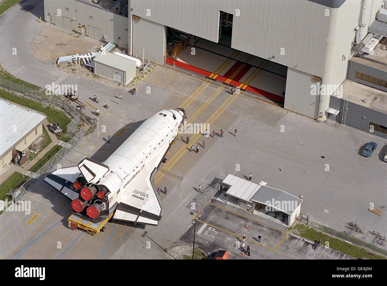 Portato sulla cima di un orbiter transporter, lo Space Shuttle orbiter Atlantis rotola fuori di Orbiter Processing Facility (OPF) Bay 3, in background, lungo il tragitto per il gruppo di veicoli Edificio (VN). Questa foto è stata scattata dal tetto del VAB. Il ribaltamento dell'orbiter è stata una delle pietre miliari prelaunch per qualsiasi volo navetta. Atlantis è di essere pronti per la sua prossima missione STS-86, che è stato oggetto di un Settembre 1997 lancio. STS-86 era il settimo di nove porti di scalo previsto della navetta spaziale orbitare con il russo della stazione spaziale Mir. Immagine # : 97PC-1225 Data: 11 Agosto 1997 Foto Stock