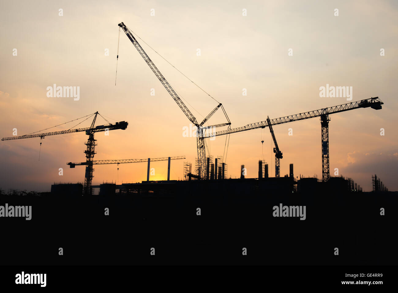 Industrial gru da cantiere di lavoro e di costruzione presso il sito dell'orario del tramonto. Foto Stock