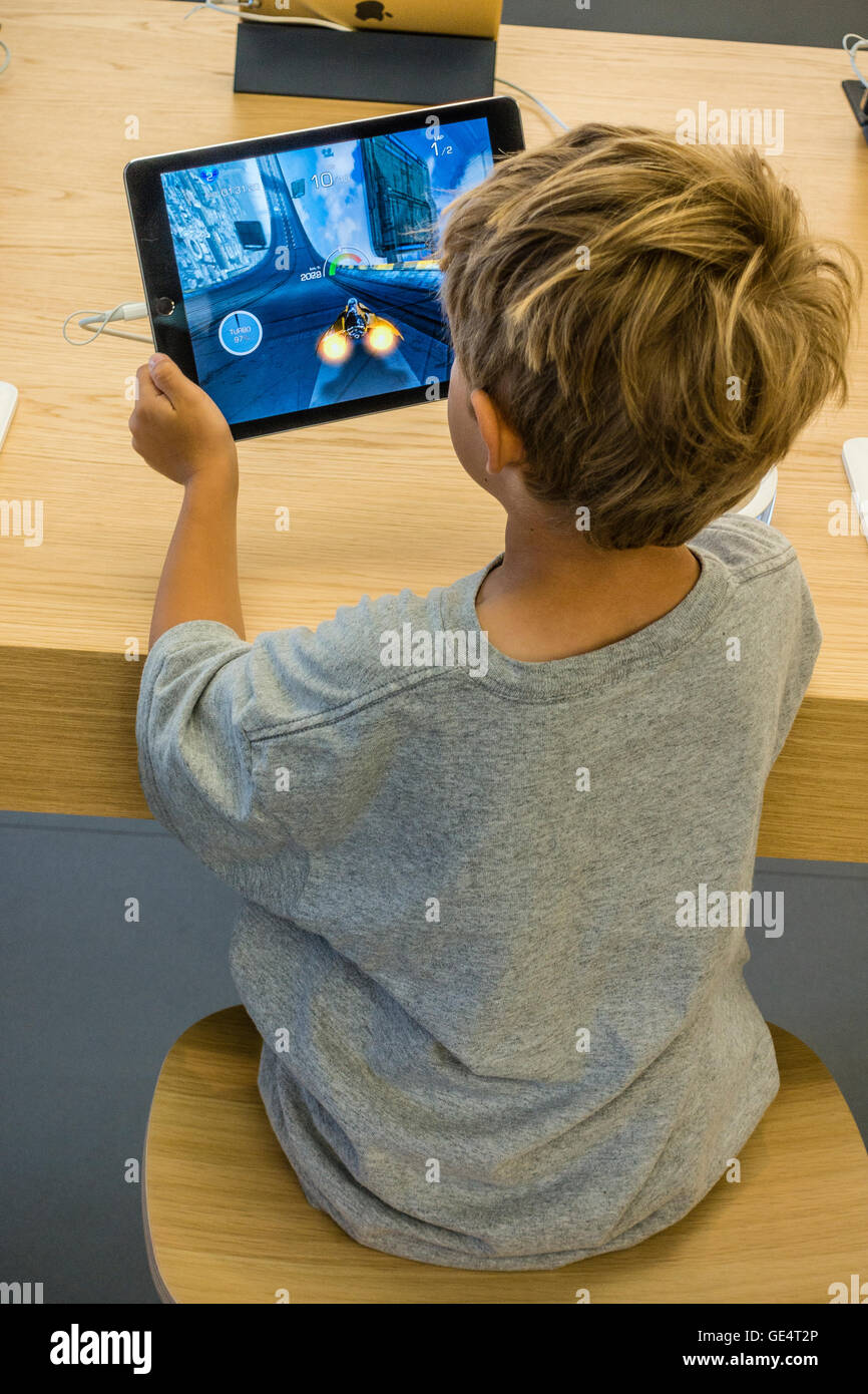 Un giovane ragazzo 7-8 anni gioca un gioco su un iPad all'Apple Store di Santa Barbara in California. Foto Stock
