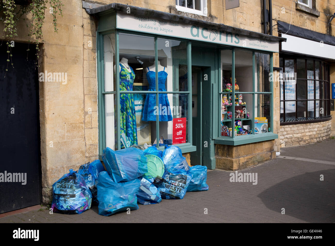 Blue sacchi di polietilene di rifiuti generali al di fuori del negozio di carità Moreton-in-Marsh Regno Unito Foto Stock