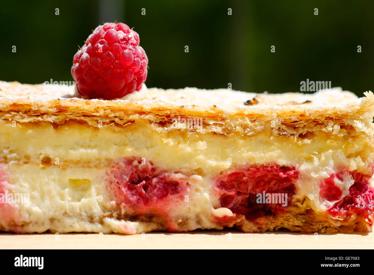 Una gustosa deliziosa cercando di lamponi freschi, pasta sfoglia, crema fetta torta decorata con un lampone sulla parte superiore Foto Stock