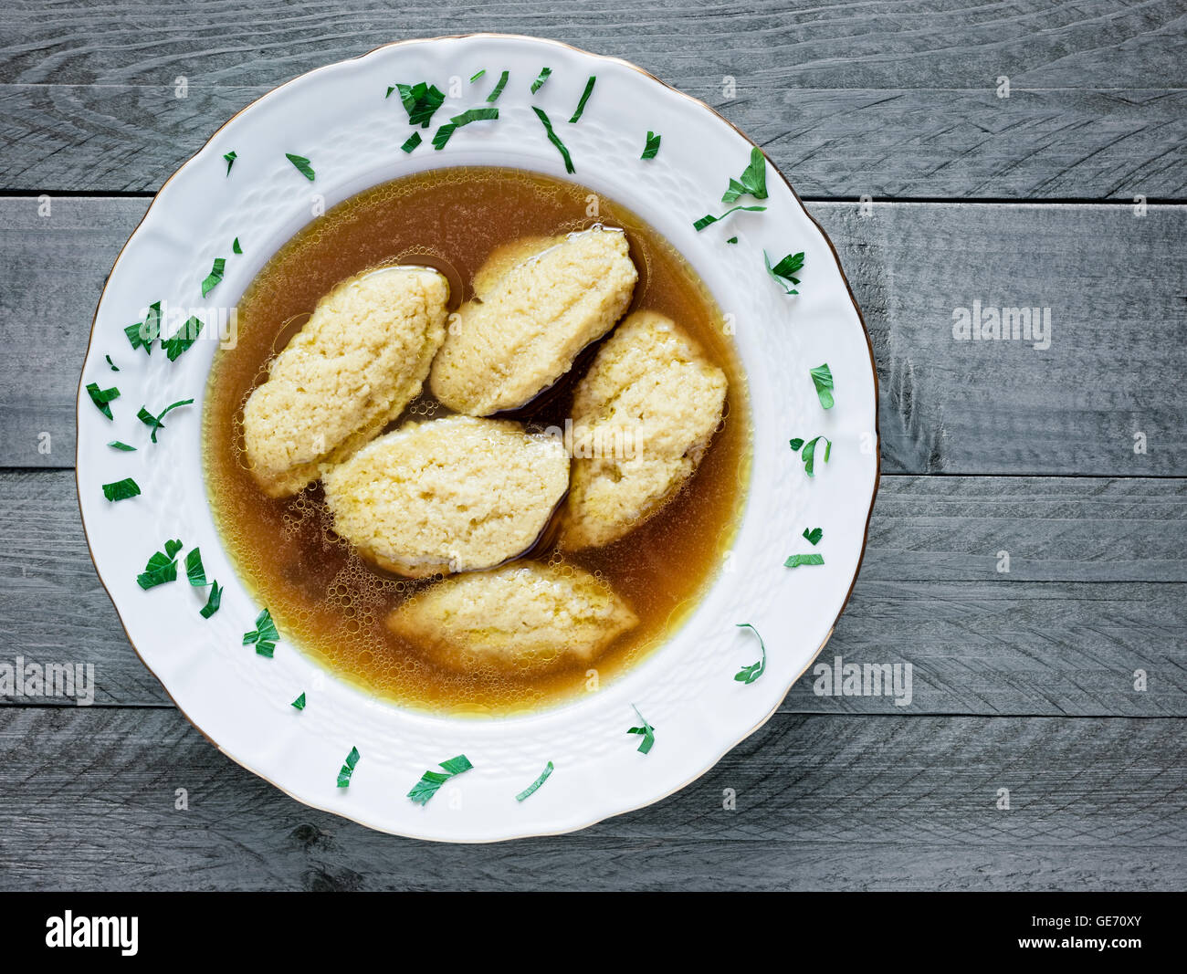 In casa di brodo di pollo con gnocchi di semolino su un grigio ardesia sullo sfondo di legno Foto Stock