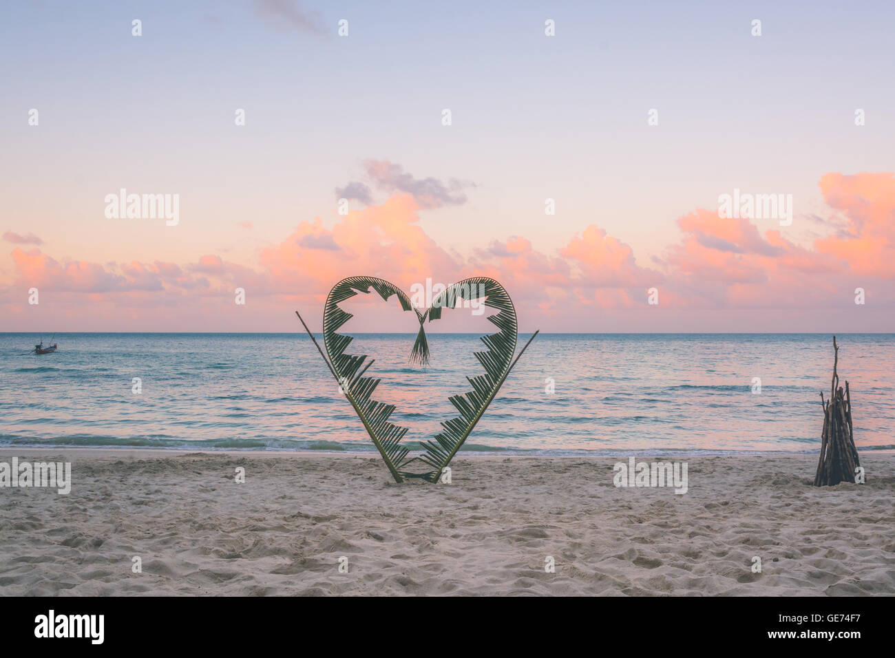 Palm tree rami sono legati a forma di cuore, su una tranquilla spiaggia dell'isola di Koh Pha Ngan, della Thailandia . Foto Stock