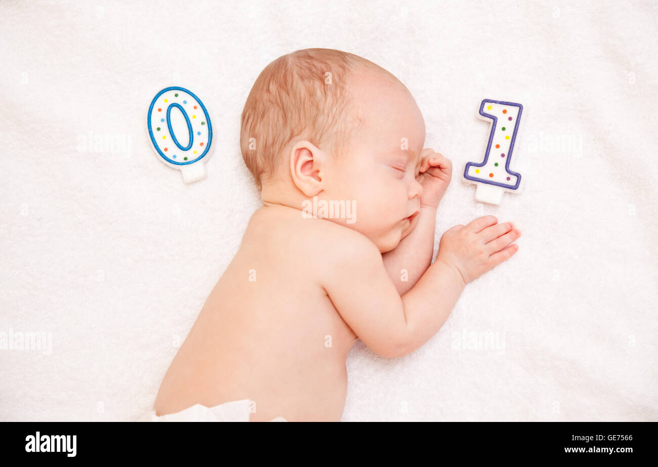 Immagine del neonato sdraiato sul letto su asciugamano bianco con candela Foto Stock