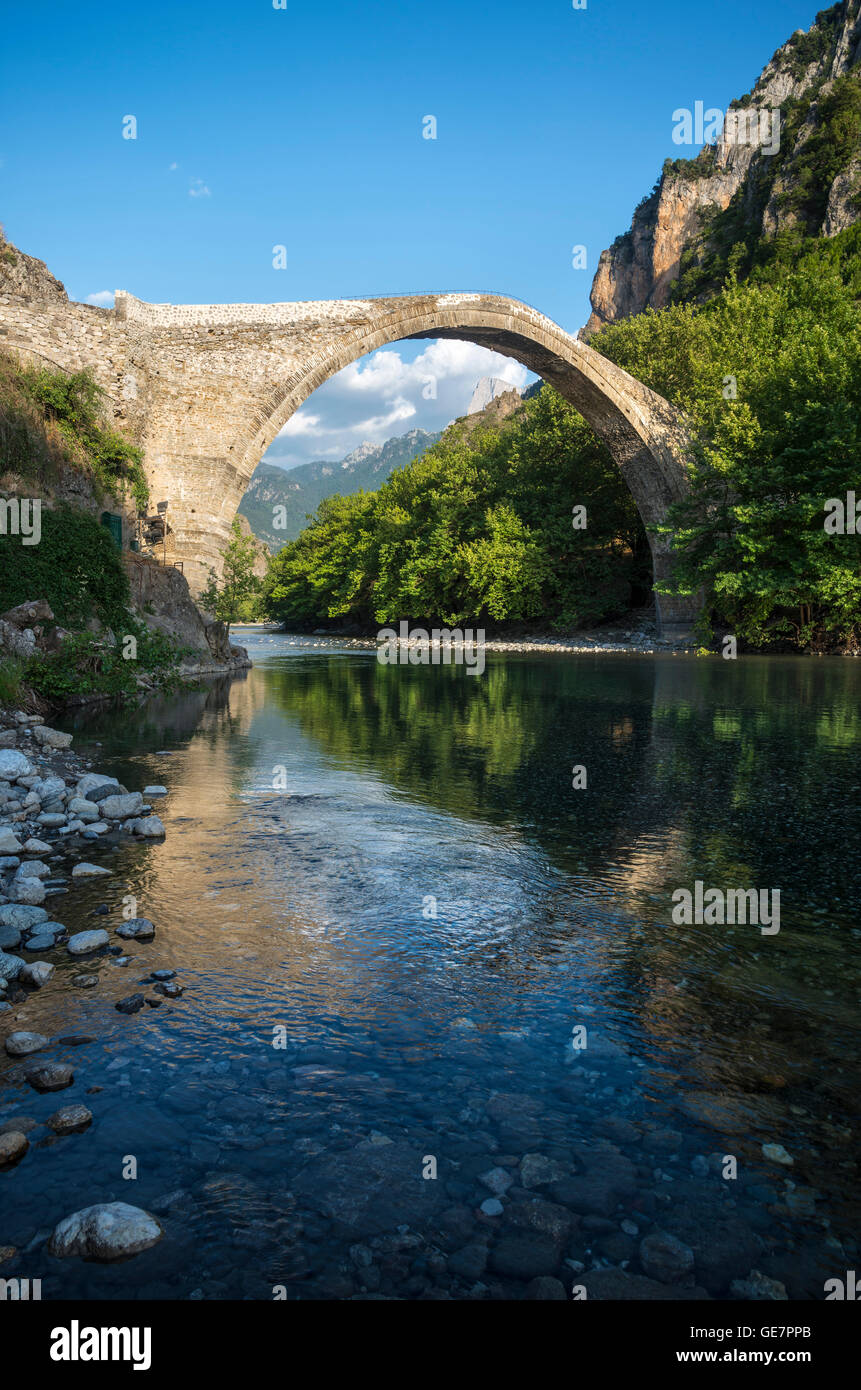 Il vecchio ponte in pietra attraverso il fiume Aoos in Konitsa con montatura Tymfi in background, Epiro, nel nord della Grecia. Foto Stock