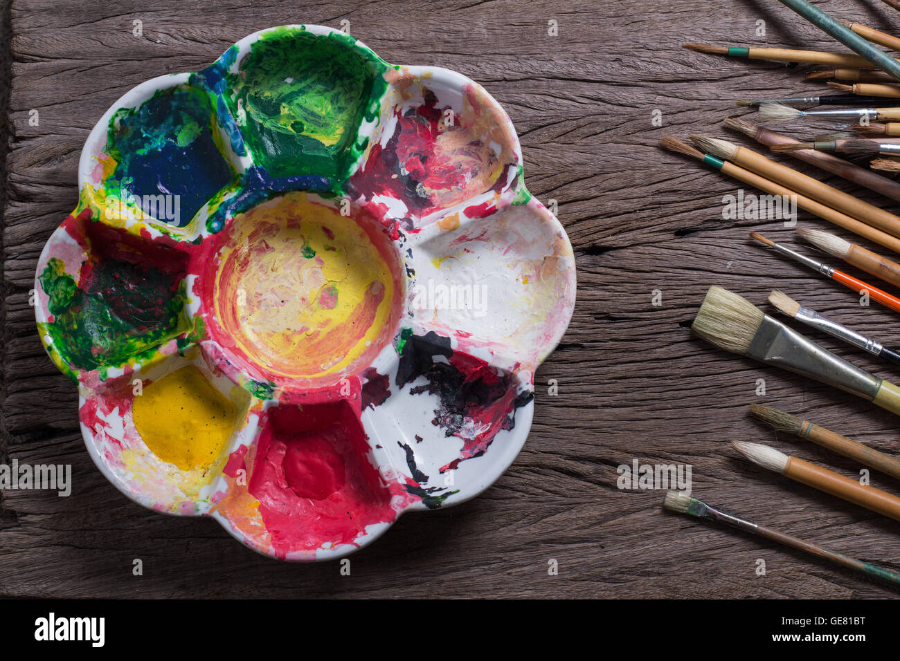 Spazzole e variopinti colori astratti pittori utilizzati pallet sul vecchio sfondo di legno Foto Stock