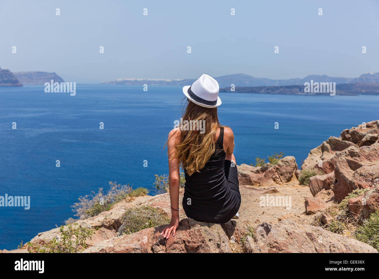 Giovane ragazza in un abito nero guardando il mare Foto Stock