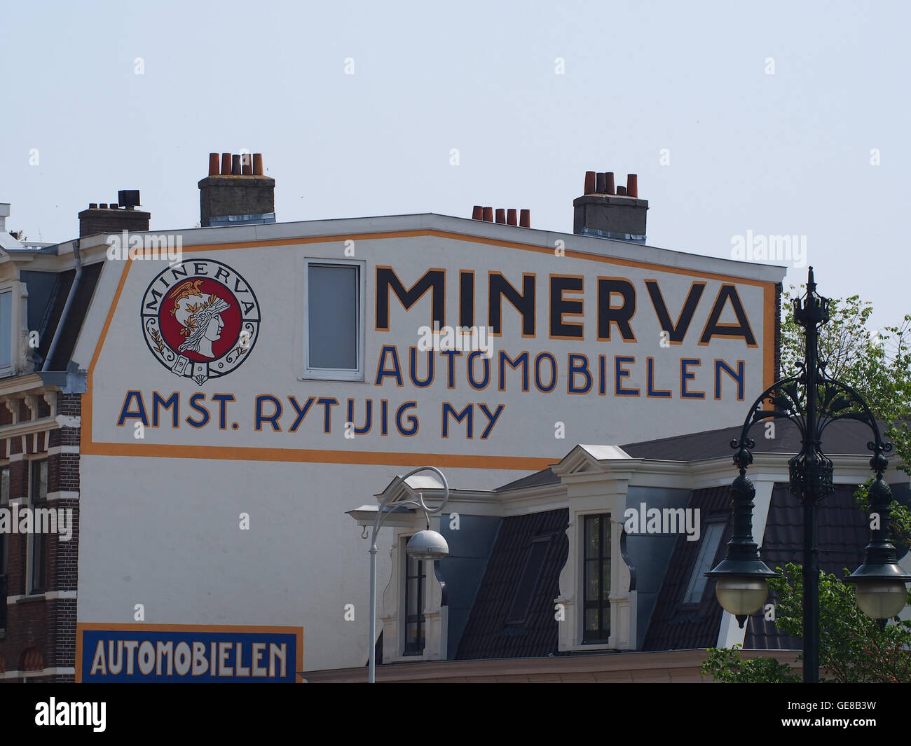 L'immagine presenta una pubblicità a parete per Minerva Automobielen, situata all'incrocio tra Blasiusstraat e Weesperzijde. Minerva era una rinomata casa automobilistica olandese, e il murale raffigura la loro eredità automobilistica. La posizione è ad Amsterdam, riflettendo sia gli elementi storici che commerciali della città. Foto Stock