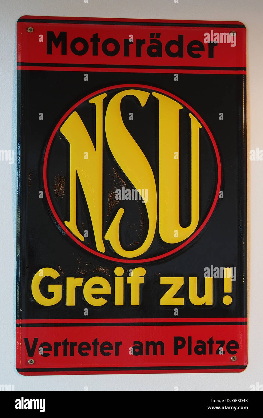 Questa pubblicità in smalto di NSU Motorraeder promuove il marchio motociclistico tedesco, mostrando il design elegante e le caratteristiche tecniche delle loro moto. Il pezzo è una rappresentazione vintage del marketing motociclistico dei primi anni del XX secolo. Foto Stock