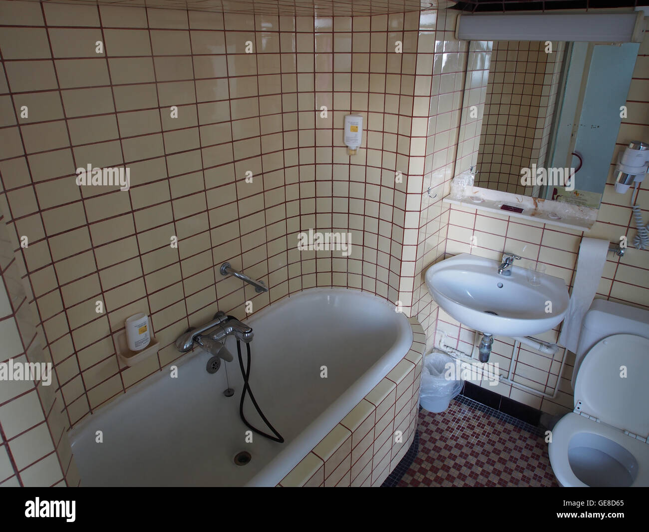 Una fotografia interna che mostra un vecchio bagno con piastrelle classiche della metropolitana. L'immagine cattura l'estetica vintage, evidenziando il design semplice ma funzionale tipico dei bagni della metà del XX secolo, offrendo uno sguardo nostalgico agli stili di design degli interni del passato. Foto Stock