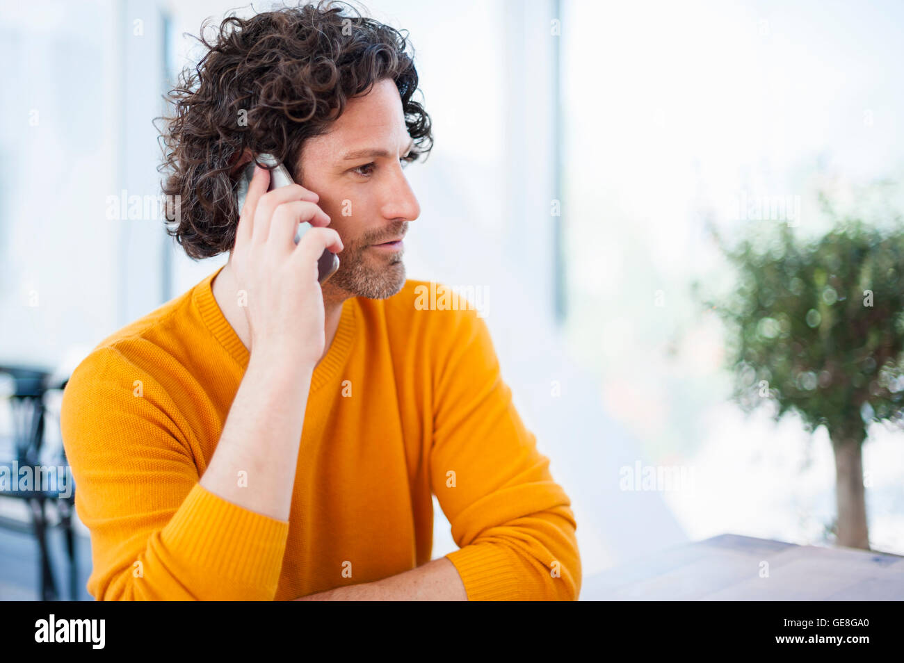 Uomo con ricci capelli castani telefonare con lo smartphone Foto Stock