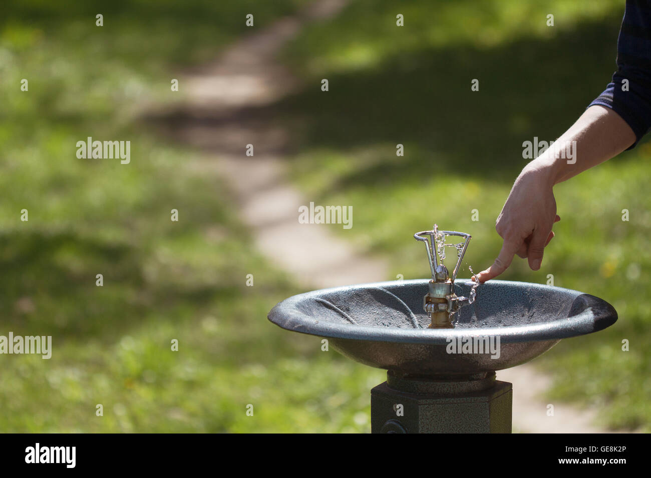 Orizzontale fino in prossimità di un lato di spinta in metallo di un erogatore di acqua in un parco verde Foto Stock