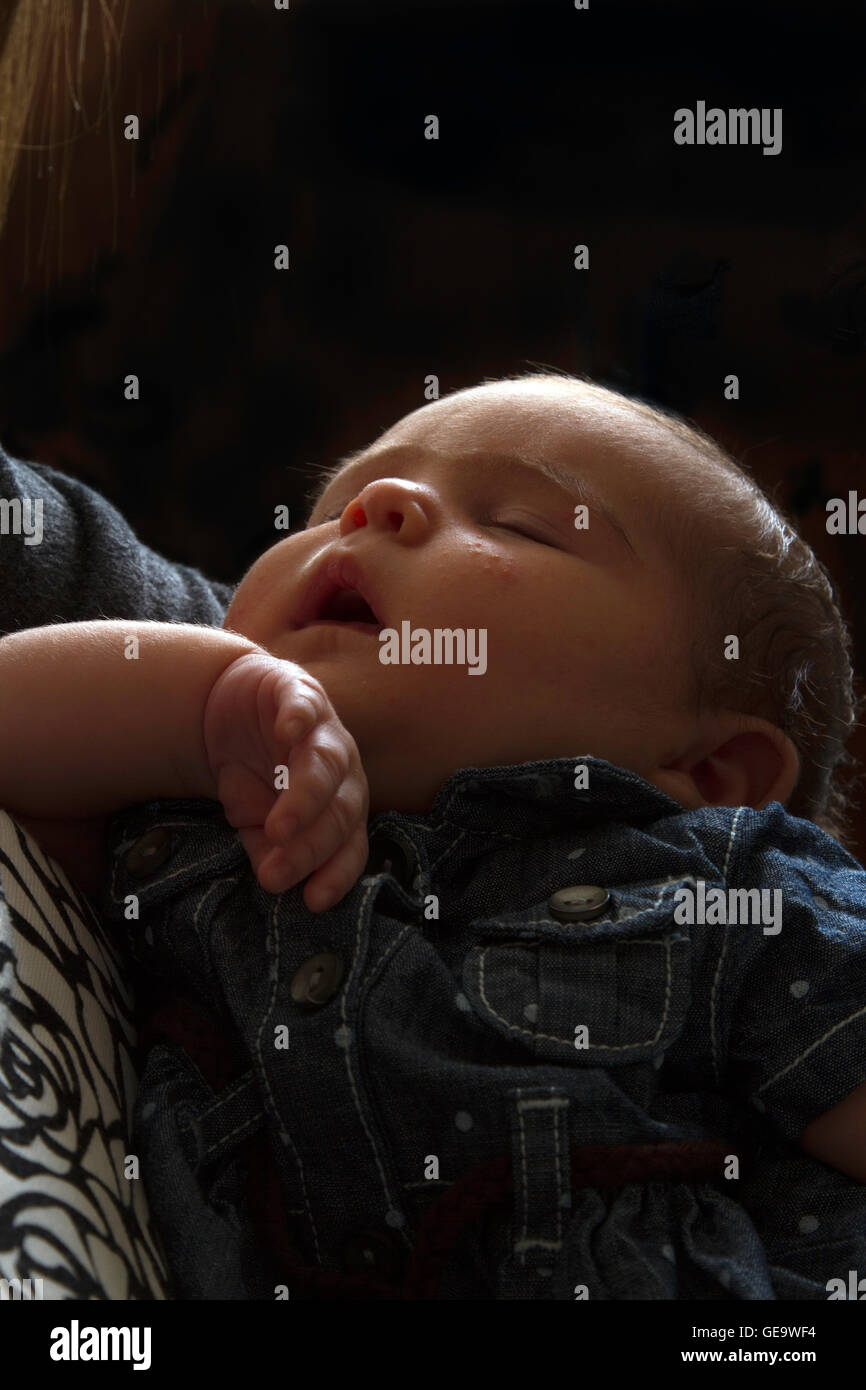 Un neonato dorme nelle sue braccia delle madri Foto Stock