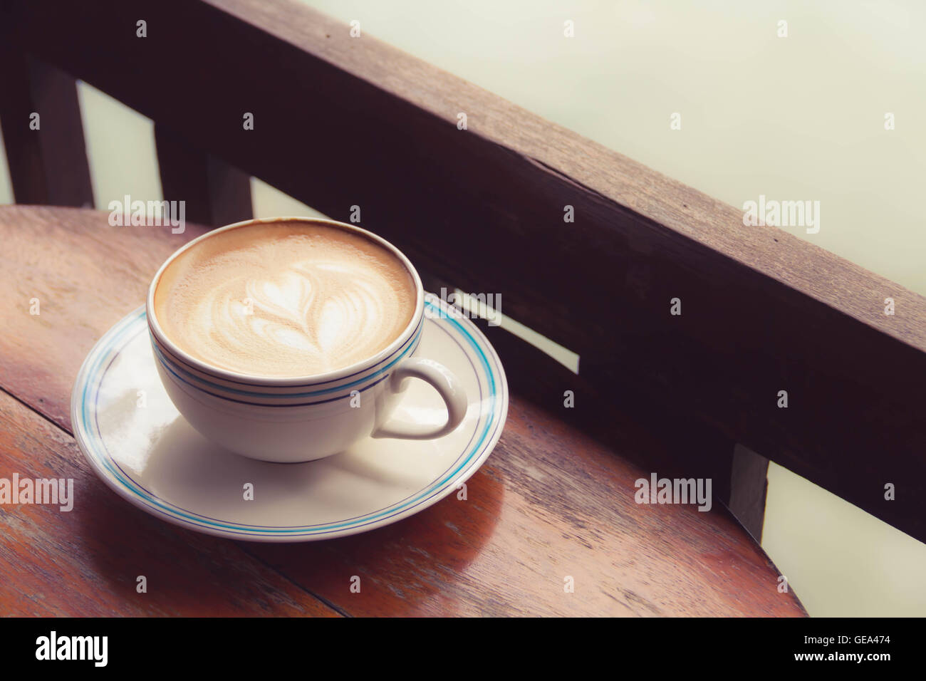 Vicino a una tazza di caffè latte art sul vecchio sfondo di legno - Vintage effetto di filtro Foto Stock