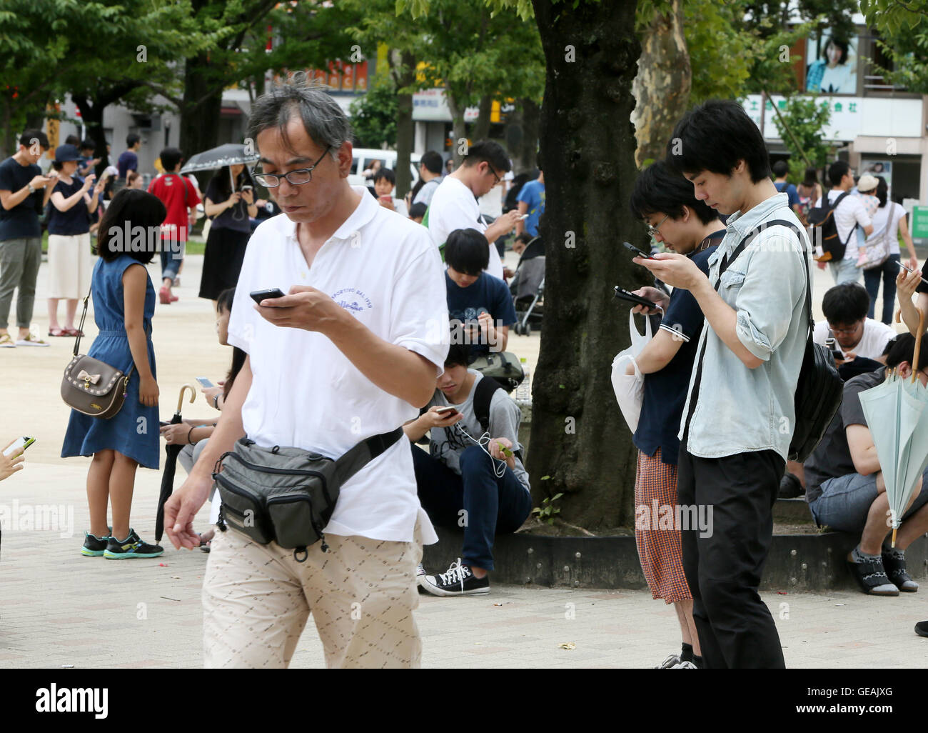 Tokyo, Giappone. Il 24 luglio, 2016. Uomini e donne giovani e non-così-vecchio sono assorbiti nella riproduzione del Pokemon Go gioco dello smartphone in un centro di Tokyo park di Domenica, 24 luglio 2016. Fin dal suo arrivo in Giappone il venerdì, l'ultima moda in tutto il mondo sta già diventando un phaenomenon sociale nel paese in cui Pokemon, breve per Pocket Monster, un gioco Nintendos app rilasciato nel 1996. Credito: Haruyoshi Yamaguchi/AFLO/Alamy Live News Foto Stock