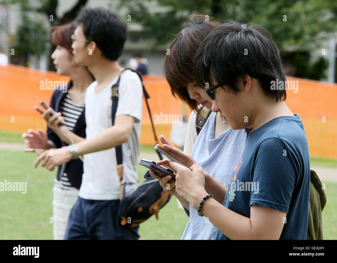 Tokyo, Giappone. Il 24 luglio, 2016. Uomini e donne giovani e non-così-vecchio sono assorbiti nella riproduzione del Pokemon Go gioco dello smartphone in un centro di Tokyo park di Domenica, 24 luglio 2016. Fin dal suo arrivo in Giappone il venerdì, l'ultima moda in tutto il mondo sta già diventando un phaenomenon sociale nel paese in cui Pokemon, breve per Pocket Monster, un gioco Nintendos app rilasciato nel 1996. Credito: Haruyoshi Yamaguchi/AFLO/Alamy Live News Foto Stock