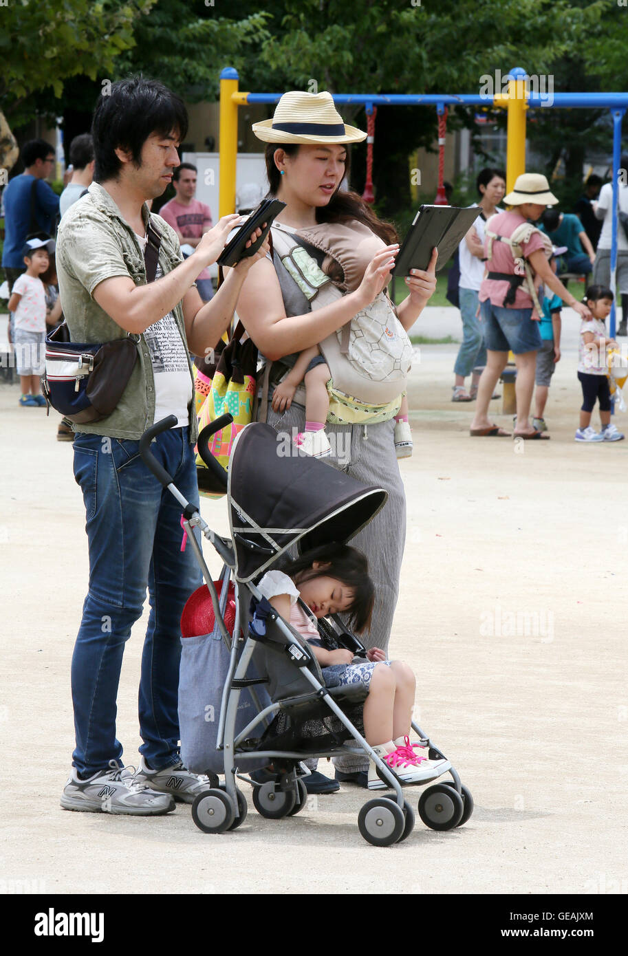 Tokyo, Giappone. Il 24 luglio, 2016. Uomini e donne giovani e non-così-vecchio sono assorbiti nella riproduzione del Pokemon Go gioco dello smartphone in un centro di Tokyo park di Domenica, 24 luglio 2016. Fin dal suo arrivo in Giappone il venerdì, l'ultima moda in tutto il mondo sta già diventando un phaenomenon sociale nel paese in cui Pokemon, breve per Pocket Monster, un gioco Nintendos app rilasciato nel 1996. Credito: Haruyoshi Yamaguchi/AFLO/Alamy Live News Foto Stock