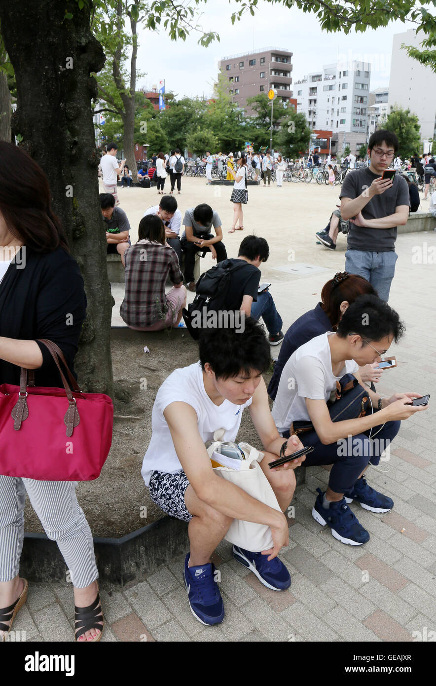 Tokyo, Giappone. Il 24 luglio, 2016. Uomini e donne giovani e non-così-vecchio sono assorbiti nella riproduzione del Pokemon Go gioco dello smartphone in un centro di Tokyo park di Domenica, 24 luglio 2016. Fin dal suo arrivo in Giappone il venerdì, l'ultima moda in tutto il mondo sta già diventando un phaenomenon sociale nel paese in cui Pokemon, breve per Pocket Monster, un gioco Nintendos app rilasciato nel 1996. Credito: Haruyoshi Yamaguchi/AFLO/Alamy Live News Foto Stock