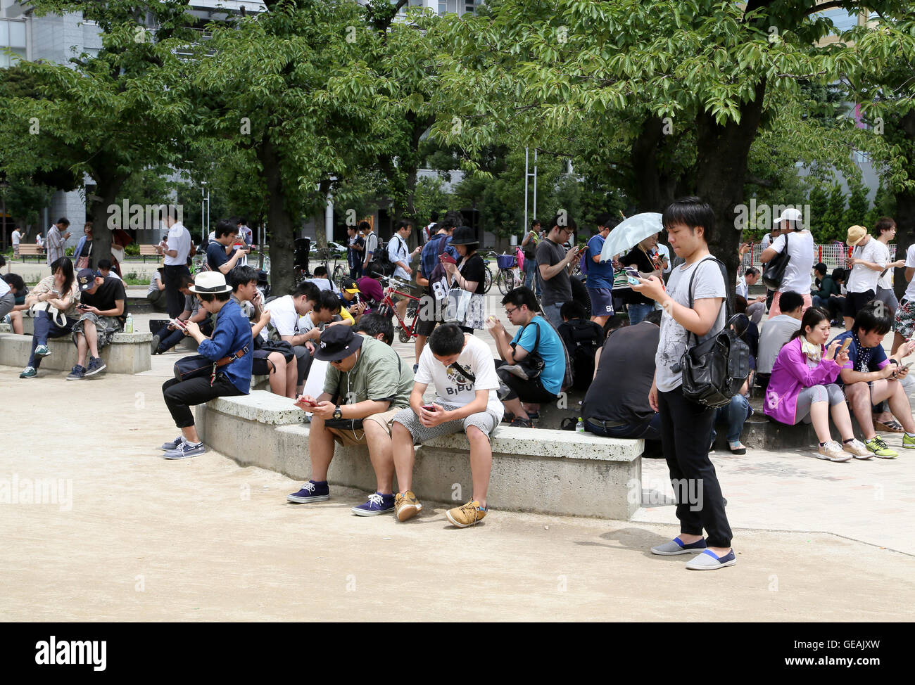 Tokyo, Giappone. Il 24 luglio, 2016. Uomini e donne giovani e non-così-vecchio sono assorbiti nella riproduzione del Pokemon Go gioco dello smartphone in un centro di Tokyo park di Domenica, 24 luglio 2016. Fin dal suo arrivo in Giappone il venerdì, l'ultima moda in tutto il mondo sta già diventando un phaenomenon sociale nel paese in cui Pokemon, breve per Pocket Monster, un gioco Nintendos app rilasciato nel 1996. Credito: Haruyoshi Yamaguchi/AFLO/Alamy Live News Foto Stock