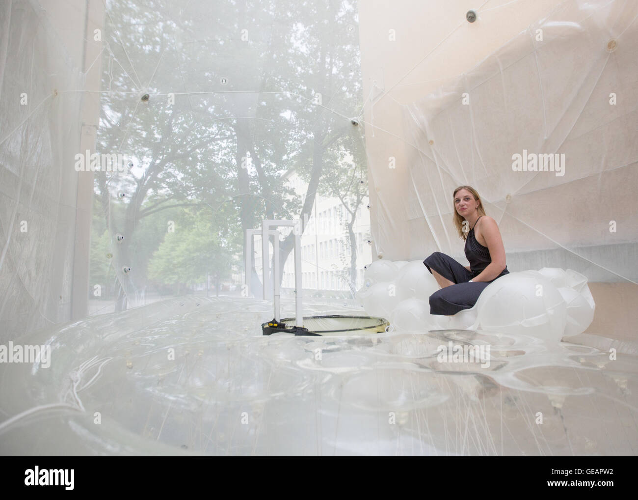 Bochum, Germania. 23 Luglio, 2016. Studente Franziska si siede in una bolla di casa tra gli edifici a Bochum, Germania, 23 luglio 2016. Il venerdì, agli studenti di architettura di Bochum ha iniziato un esperimento sul futuro delle case dello studente. Hanno installato una sorta di bolla fatta di plastica traslucida nella stretta intercapedine tra due case plurifamiliari, uno spazio di circa tre metri, che possono essere immessi utilizzando una scala su una cabina telefonica che è stato convertito in una doccia. Foto: MARCEL KUSCH/dpa/Alamy Live News Foto Stock