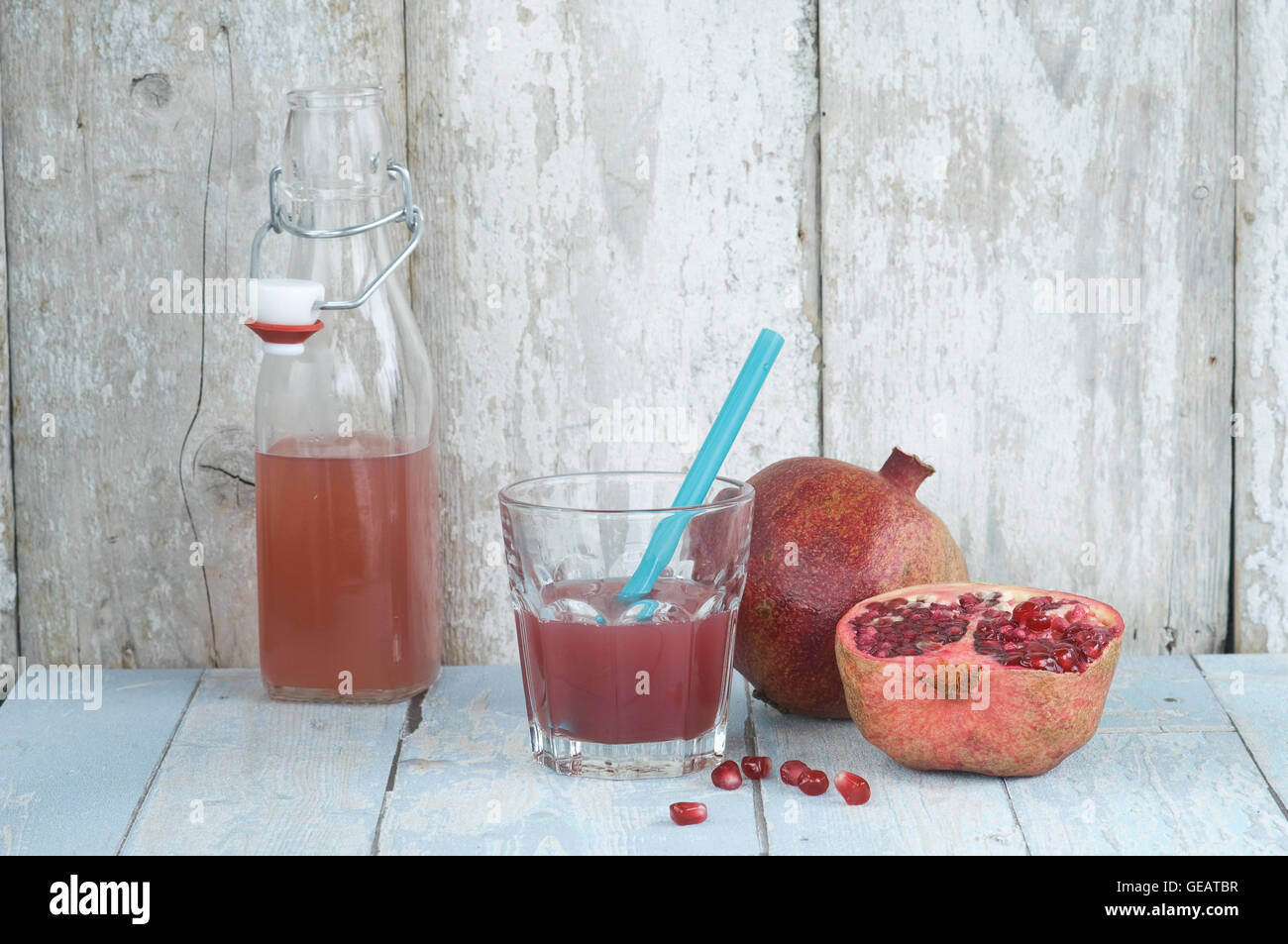 Vetro e bottiglia di succo di melograno e intera e fette di melagrana Foto Stock