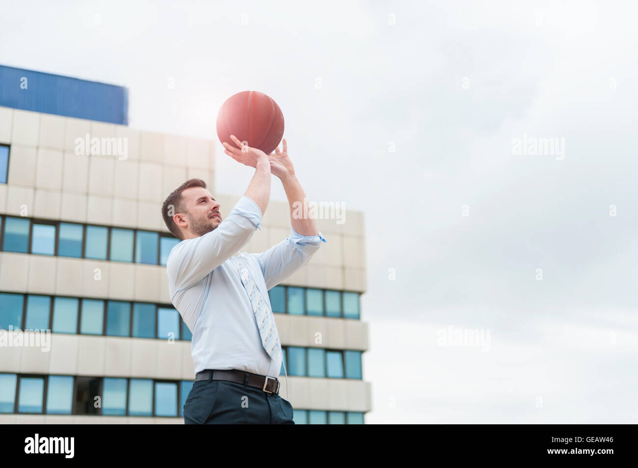 Imprenditore giocare a basket all'aperto Foto Stock