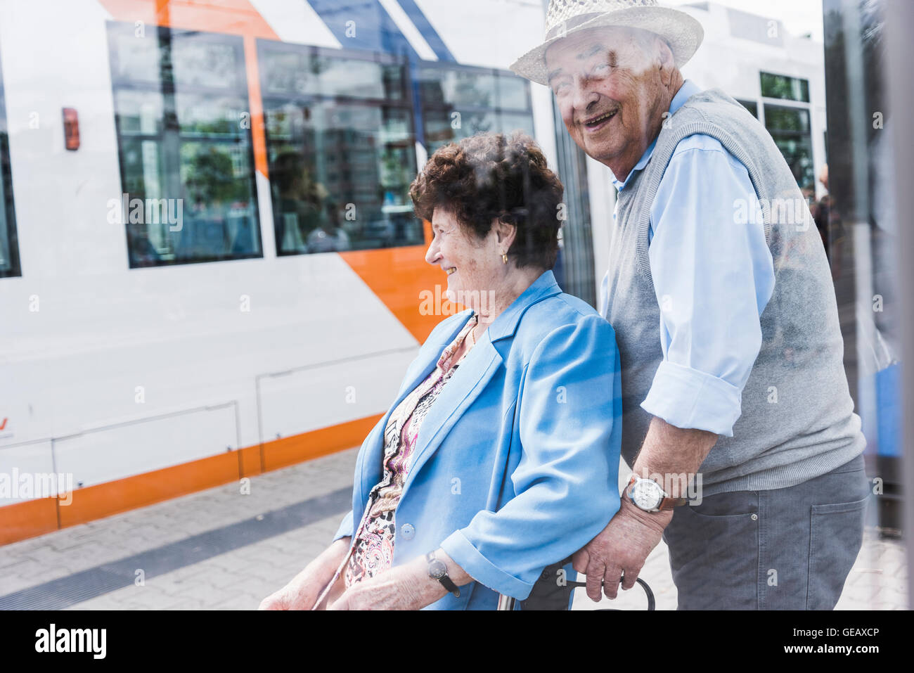 Germania, Mannheim, felice coppia senior con scuotipaglia con ruote in attesa nella stazione Foto Stock