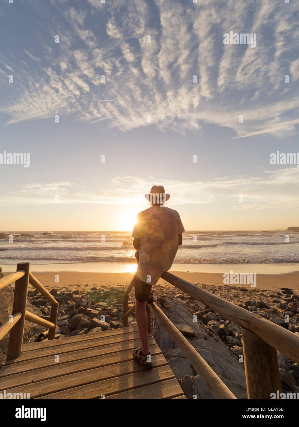 Il Portogallo, Senior uomo seduto sulla ringhiera in spiaggia Foto Stock