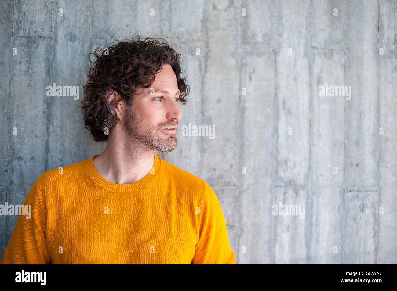 Uomo con parentesi marrone capelli appoggiata contro la parete di cemento Foto Stock