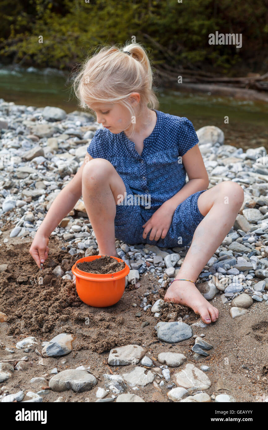 La bionda bambina gioca con la sabbia al Riverside Foto Stock