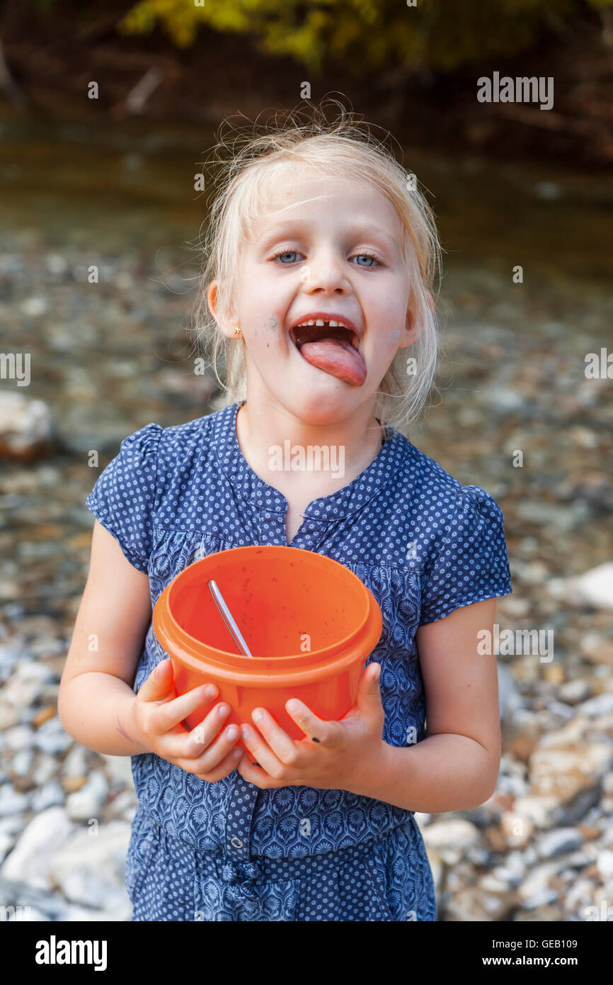 Ritratto di ragazza bionda con coppa in plastica leccare le sue labbra Foto Stock