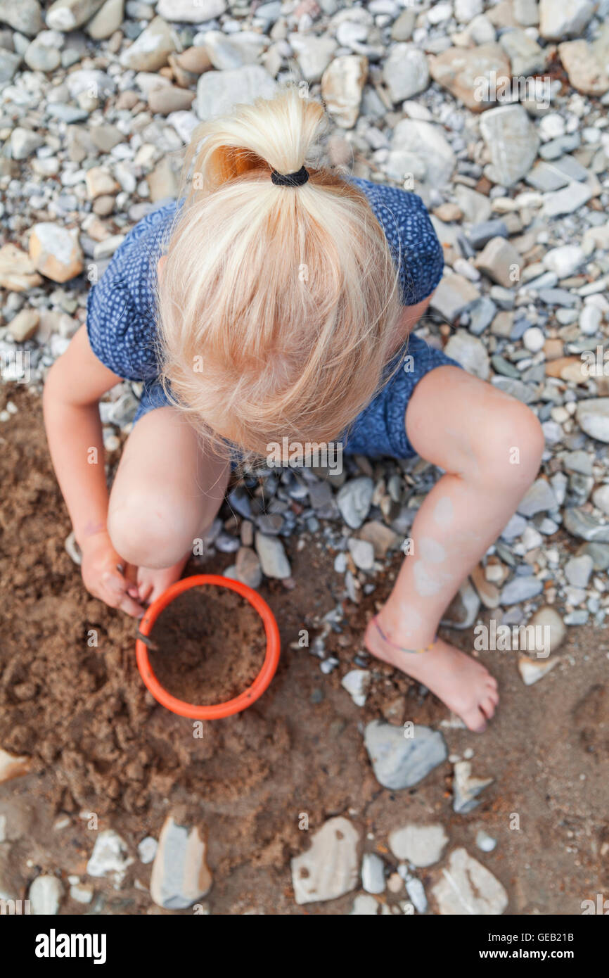 La bionda bambina gioca con la sabbia in natura Foto Stock