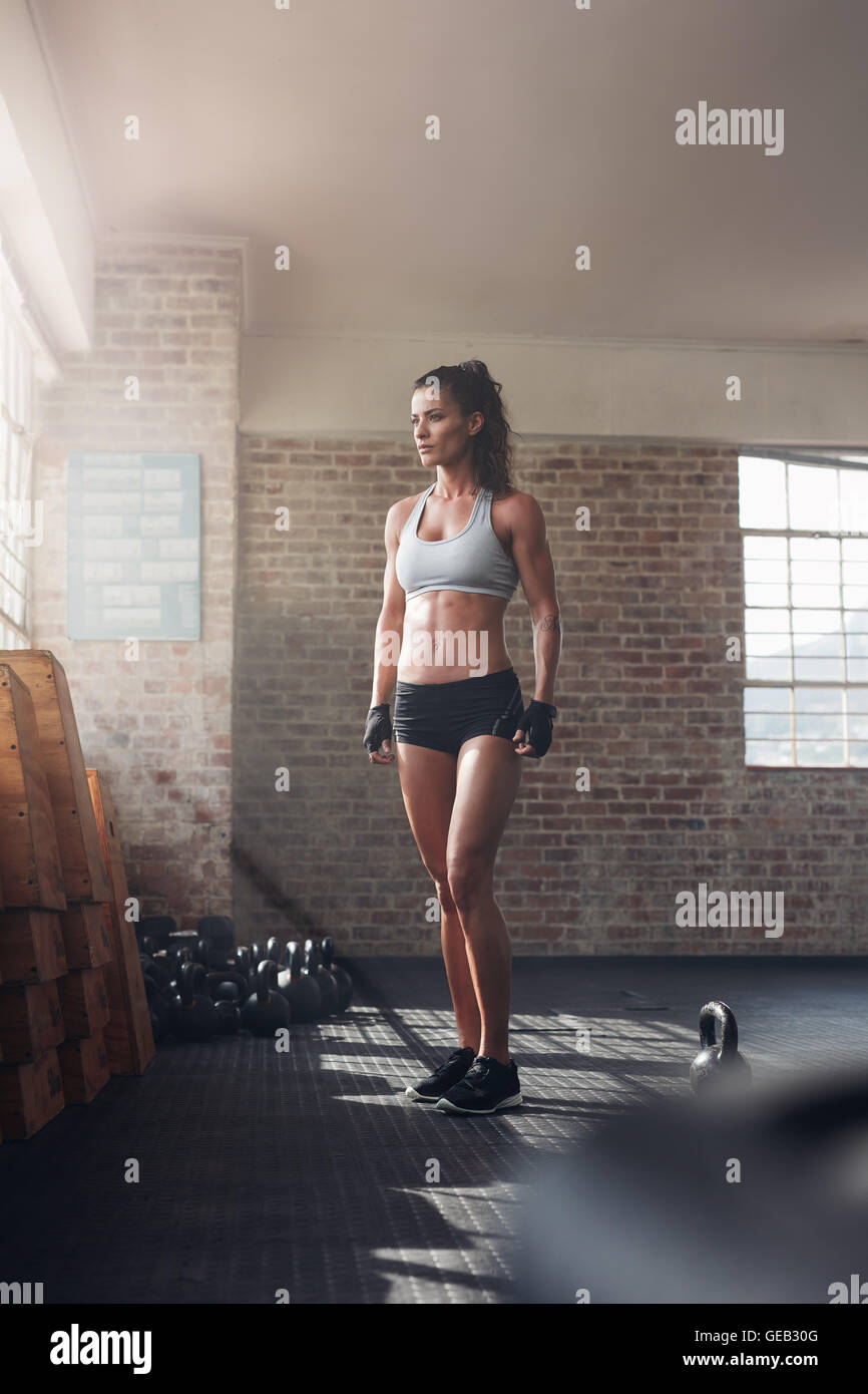 A piena lunghezza shot di donna forte in piedi in palestra crossfit e  guardando lontano. Fiducioso fitness modello femminile in abbigliamento  sportivo Foto stock - Alamy