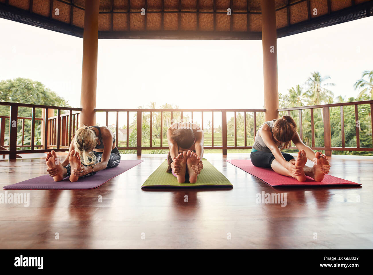 Tre donne a praticare lo yoga insieme alla classe, praticando paschimottanasana pongono. Femmine Fitness stretching in avanti nella yoga. Foto Stock
