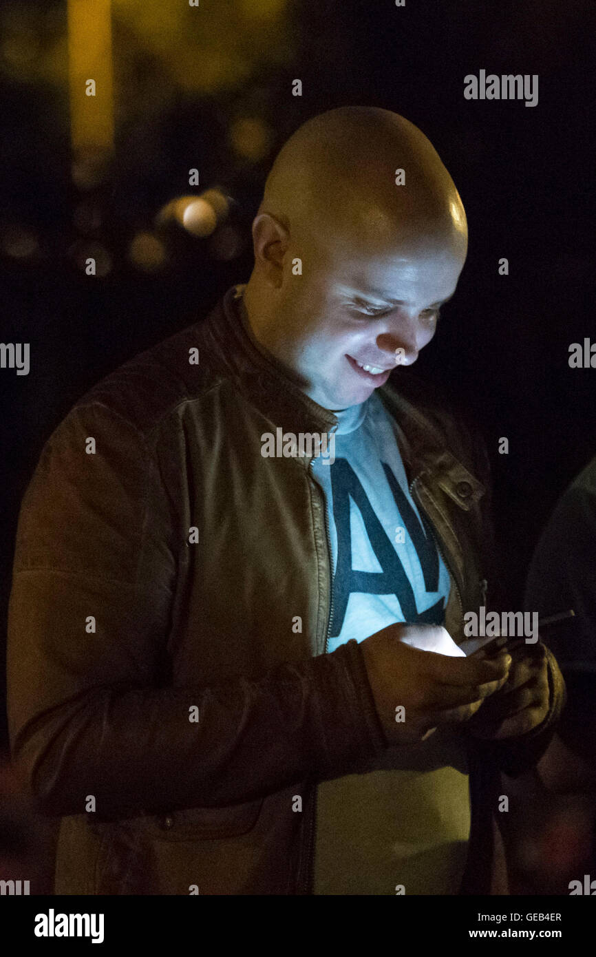 Un uomo Gioca Pokemon andare sul suo telefono cellulare di notte. Foto Stock