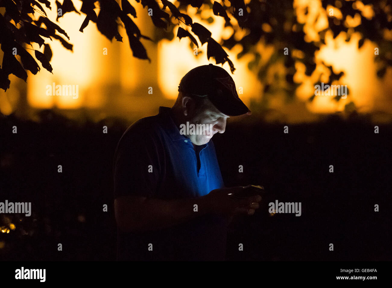 Un uomo Gioca Pokemon andare sul suo telefono cellulare di notte. Foto Stock