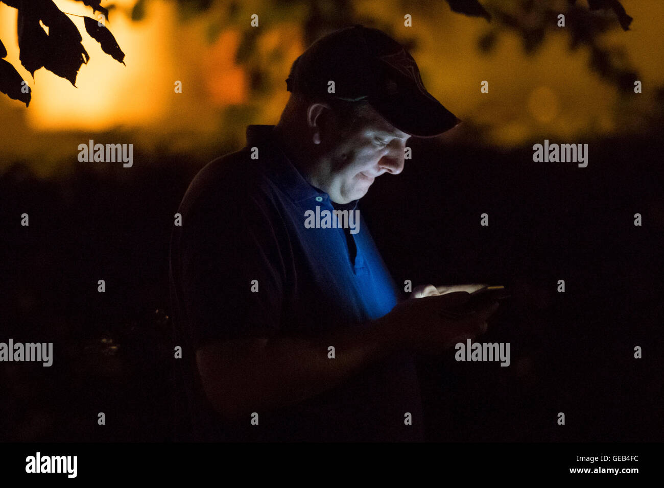 Un uomo Gioca Pokemon andare sul suo telefono cellulare di notte. Foto Stock