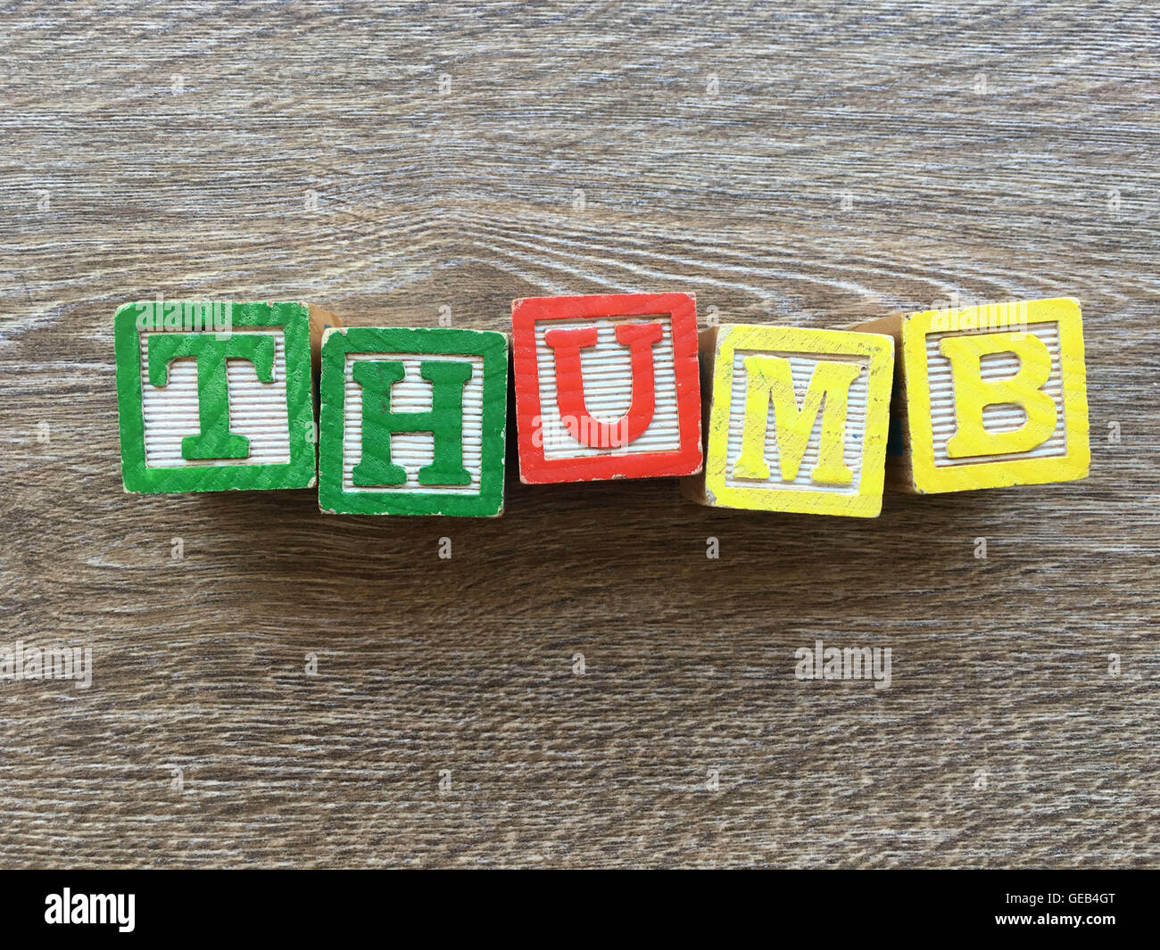 Alfabeto blocco di legno lettere che compongono la parola pollice, combinando tali giocattoli lettere aiutare i bambini ad imparare e scrivere in inglese Foto Stock
