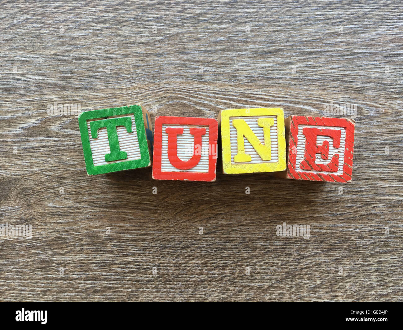 Alfabeto blocco di legno lettere che compongono la parola TUNE, combinando tali giocattoli lettere aiutare i bambini ad imparare e scrivere in inglese Foto Stock