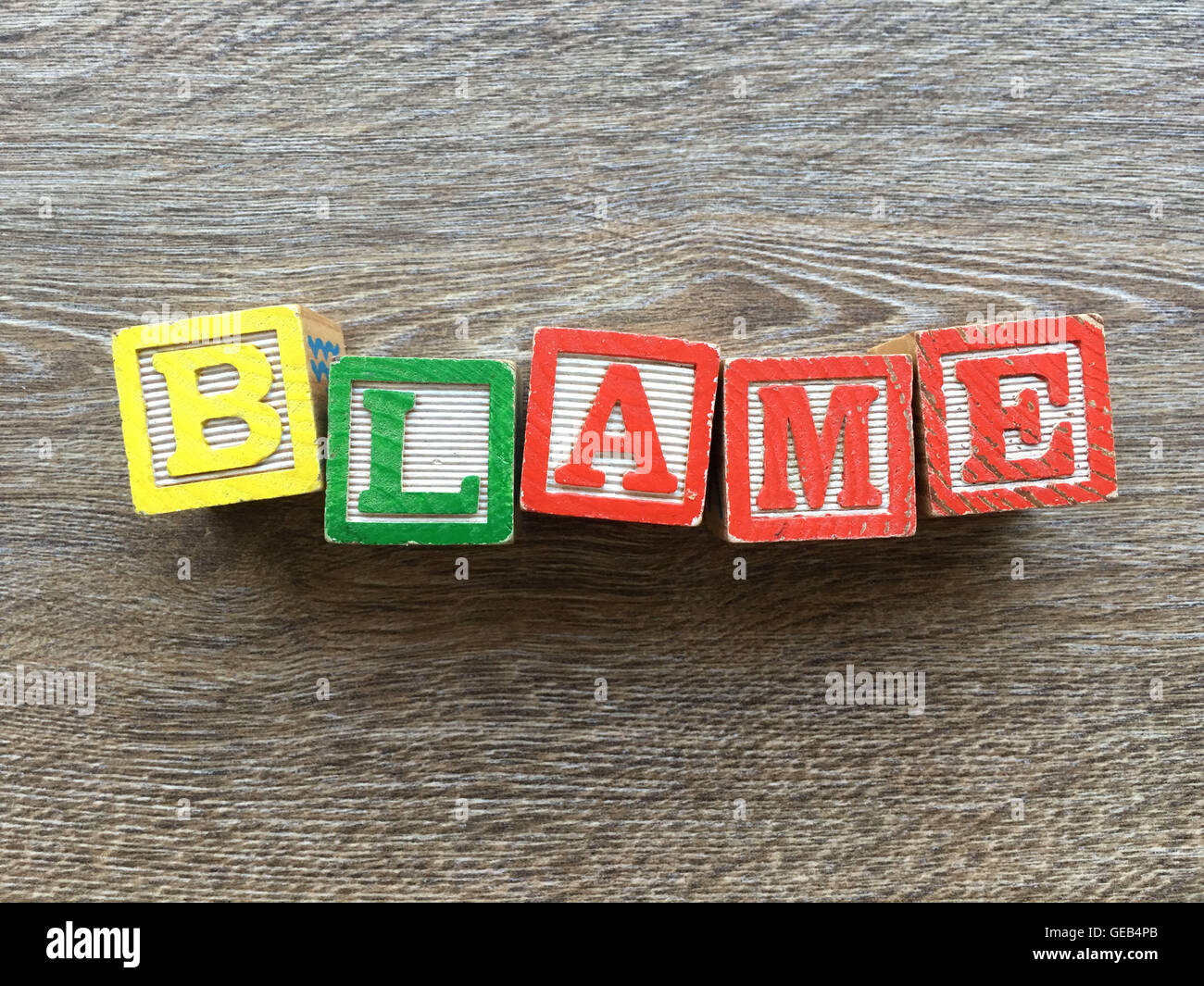 Alfabeto blocco di legno lettere che compongono il verbo di colpa, è un modo per i giovani i bambini ad imparare le parole in inglese in un modo divertente Foto Stock
