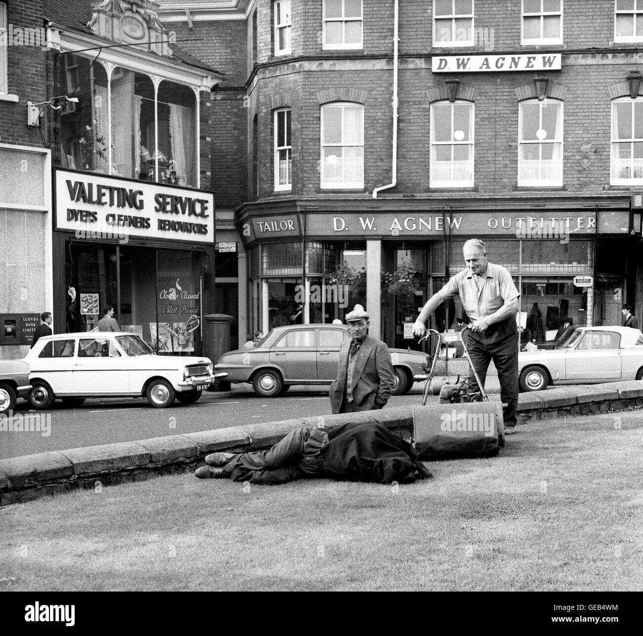 Un comunali giardiniere ha di falciare l'erba attorno ad un uomo sonno agitato Gran Bretagna 1967 anni sessanta foto di David Bagnall Foto Stock