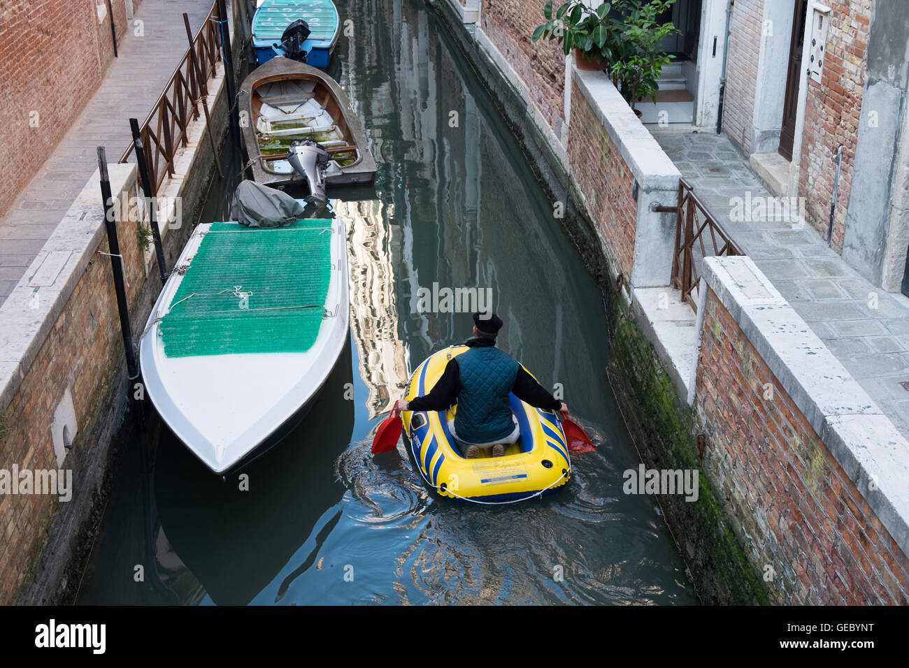 Un uomo sguazzare un dinghy in un canal Venezia Italia Foto Stock