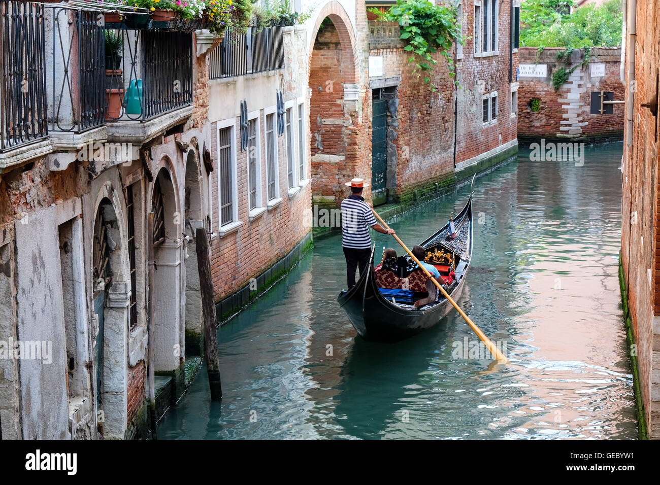 Gondoliere canottaggio la sua gondola che trasportano i turisti su un canal Venezia Italia Foto Stock