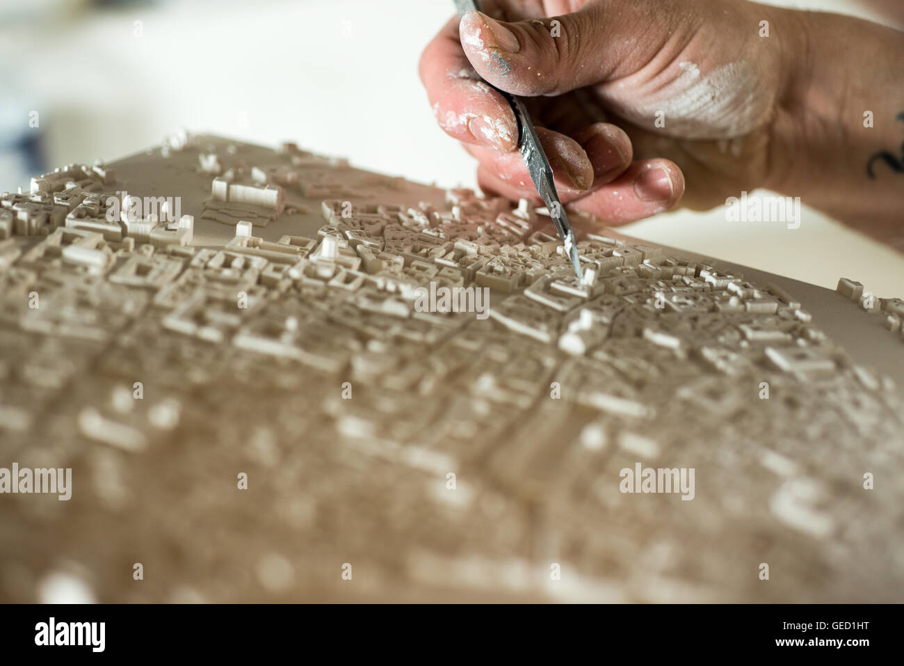 Mano con un coltello di precisione fine-ritaglio di una sezione di un 3D intonaco mappa modello Foto Stock