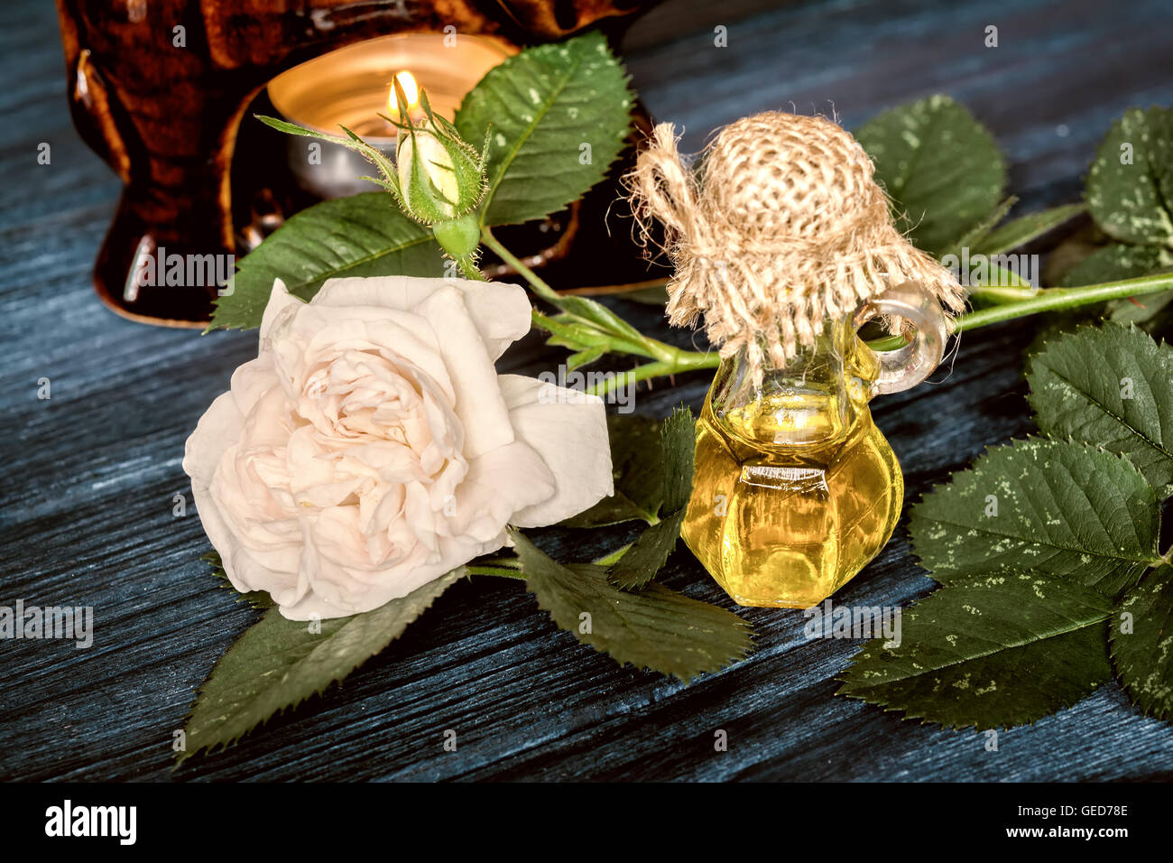 Olio essenziale di rosa sul blu scuro dello sfondo di legno. Vintage effetto tonico Foto Stock